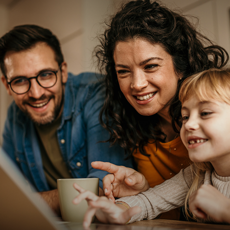Família sorridente observa um ecrã
